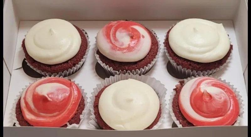 Box of six red velvet cupcakes with white and red swirled cream cheese frosting